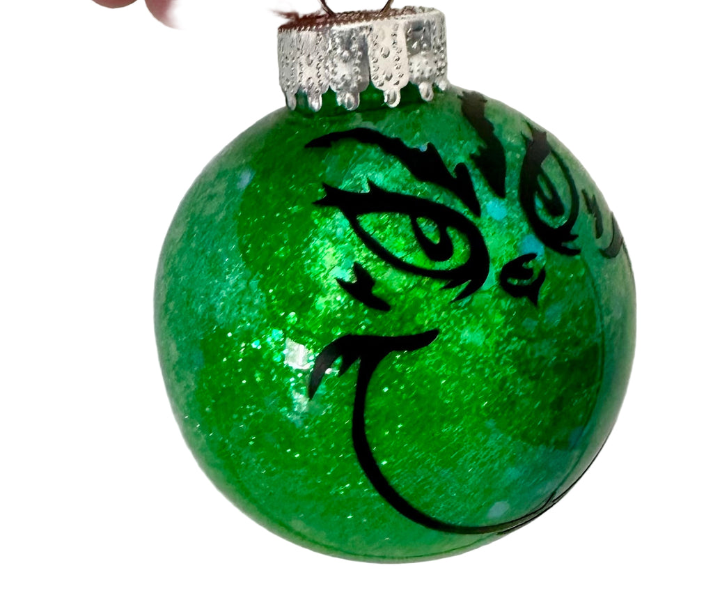 Round Christmas ornament with iconic Grinch face and blue glitter shift