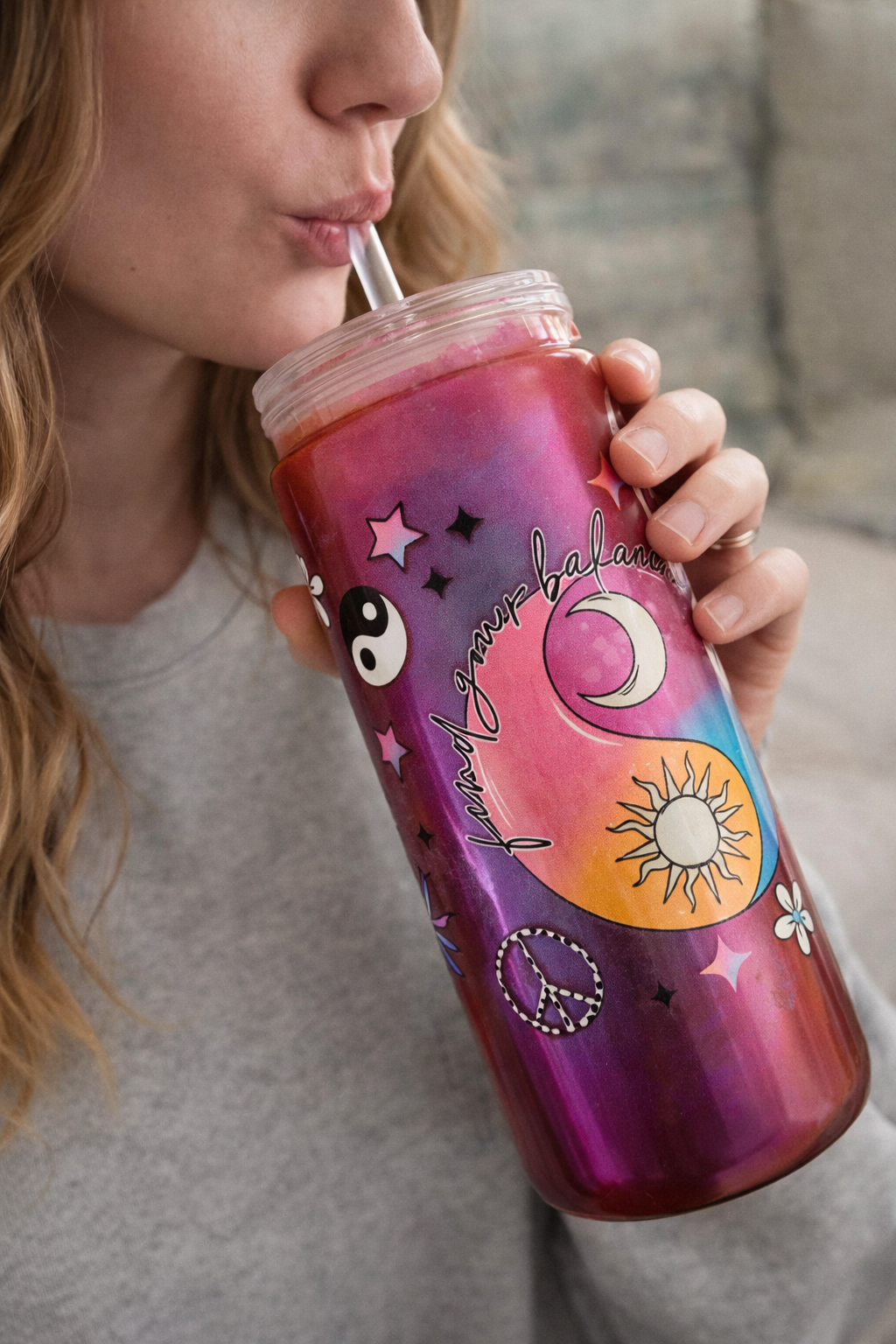 Person holding a colorful tumbler with designs and text.